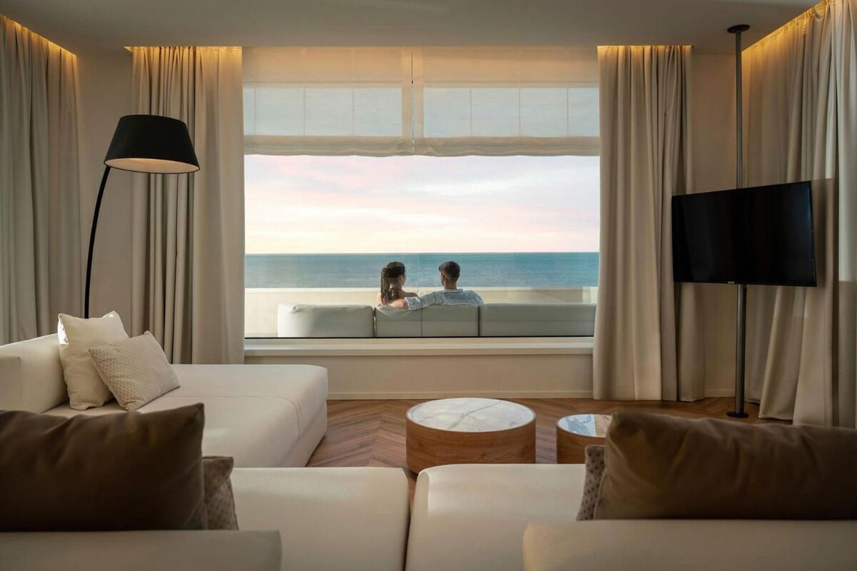 Una sala de estar moderna con un ventanal grande, un sofá, una mesa de centro y un televisor.
