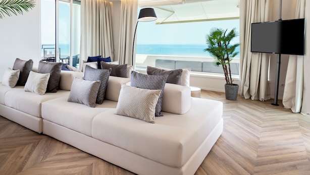 Een moderne woonkamer met een grote bank, een flatscreen televisie en uitzicht op zee.