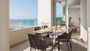 Een balkon met een ontbijttafel, met uitzicht op een strand en de zee.