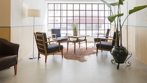 Un salón amplio con un gran ventanal, un sofá de cuero, sillas de madera, una mesa de centro y una planta en maceta.