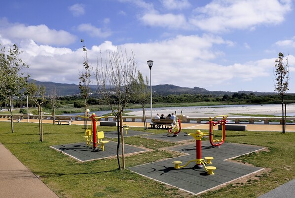 An outdoor exercise area with fitness equipment, benches, and a path.