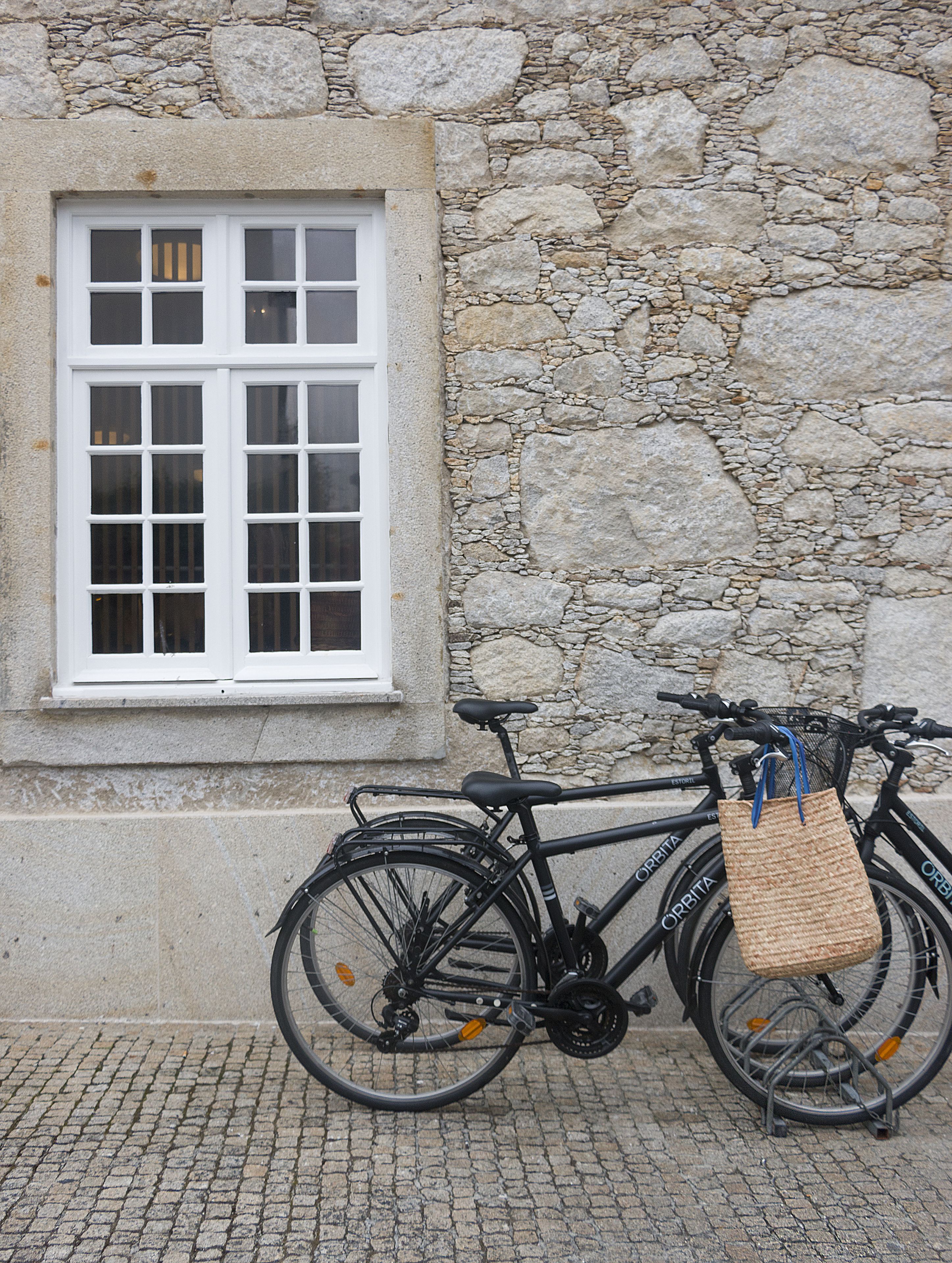 A bicycle parked against a stone wall with a window.