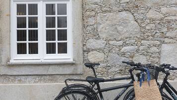 A bicycle parked against a stone wall with a window.