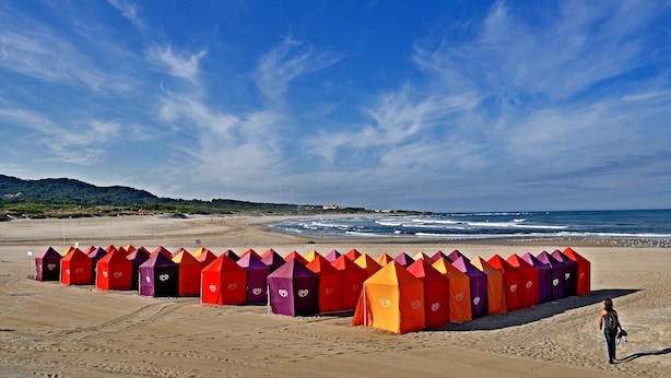 Una playa con carpas coloridas dispuestas en filas.