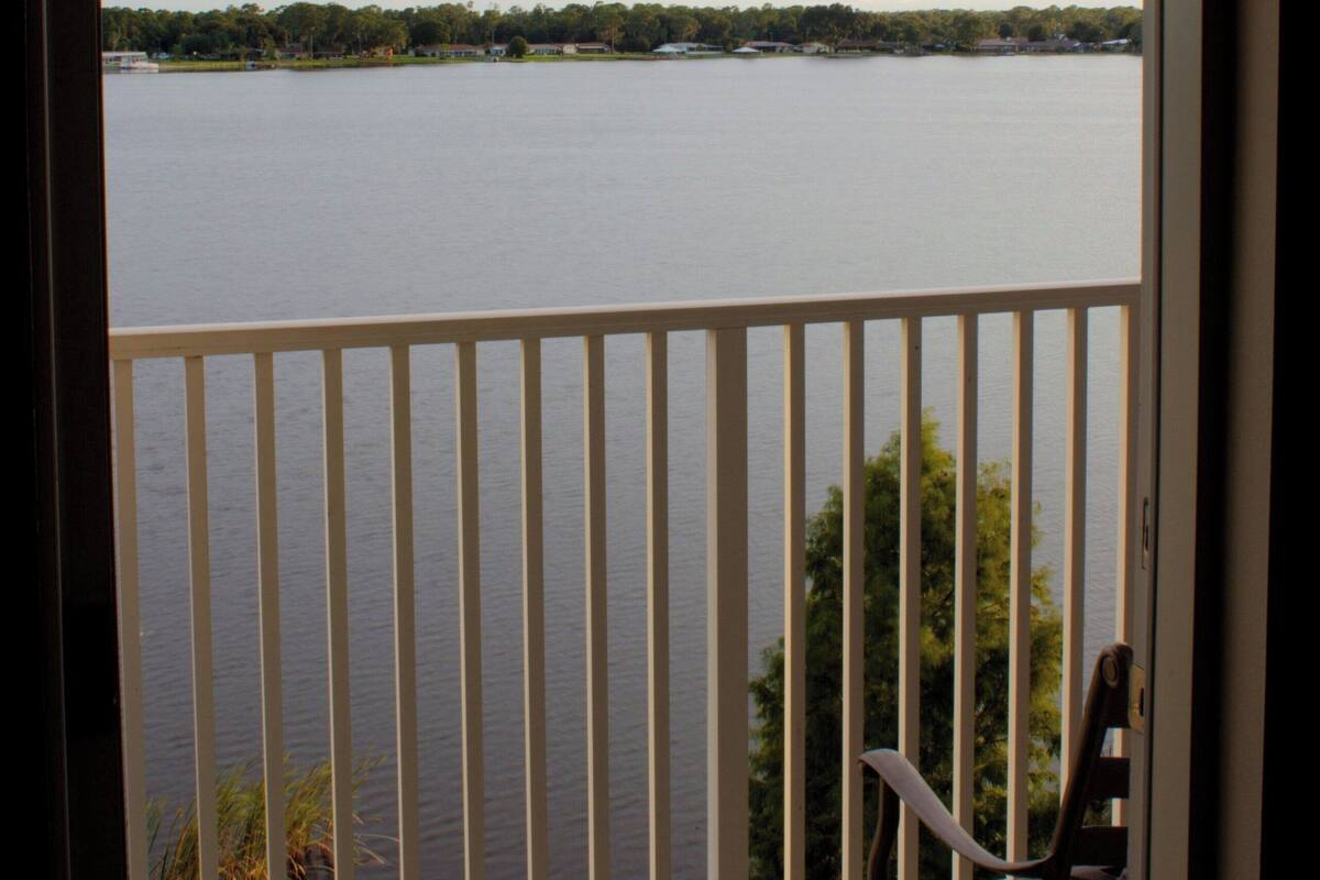 A balcony with a view of a lake and distant shoreline.
