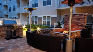 Une terrasse extérieure équipée d’un barbecue, de sièges et d’un foyer.