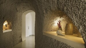 An interior with a textured stone wall, a white door, and a shelf with decorative items.