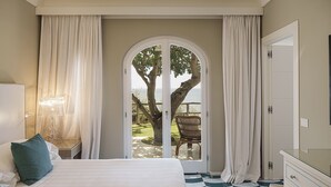 A bedroom with a large bed, a view of the outdoors through a glass door, a chair outside, and a dresser with drawers.