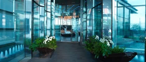 Een moderne hotel lobby met glazen wanden, een centrale trap en potplanten.