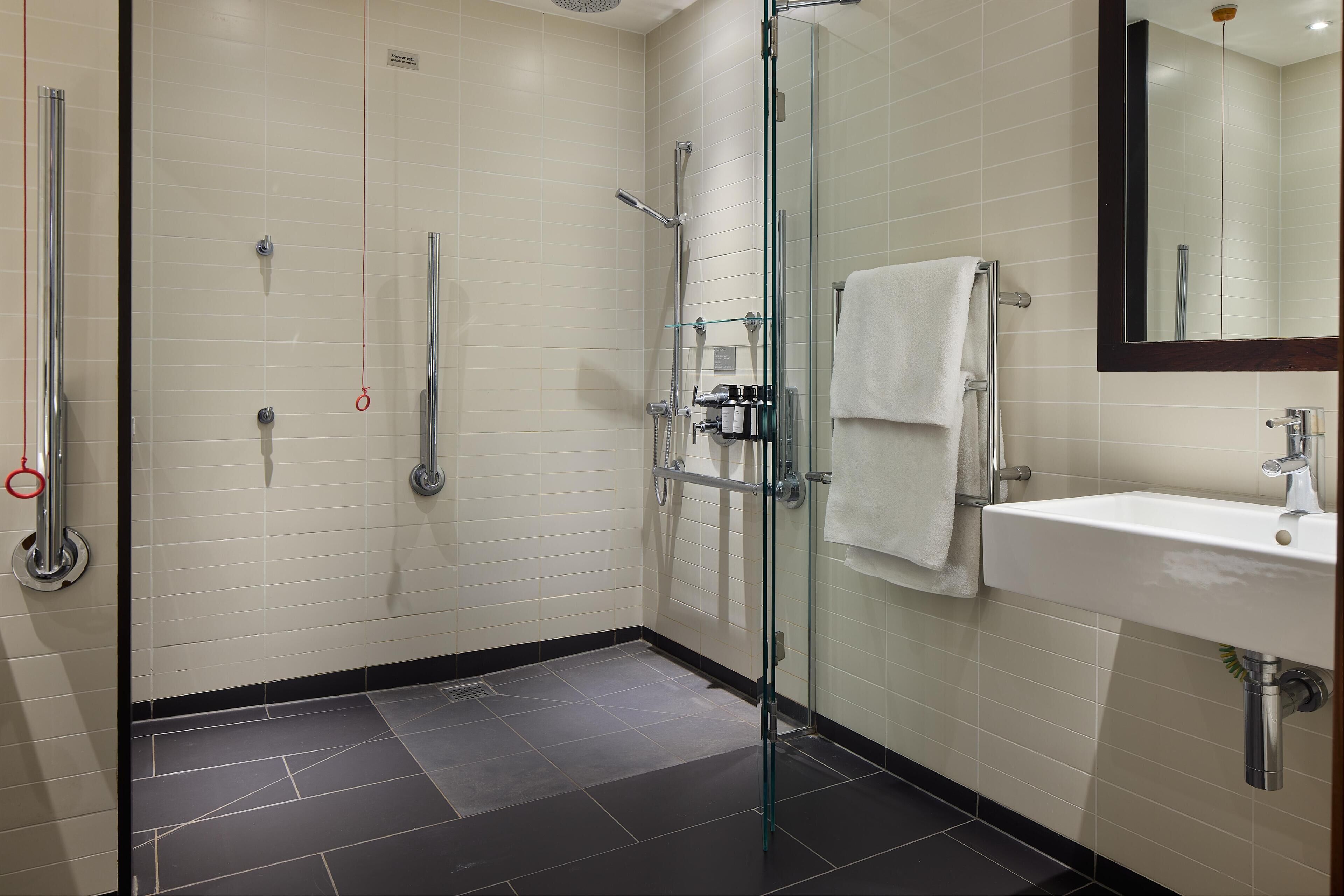 A modern bathroom with a glass shower enclosure, a white sink, and a mirror.