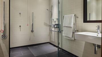 A modern bathroom with a glass shower enclosure, a white sink, and a mirror.