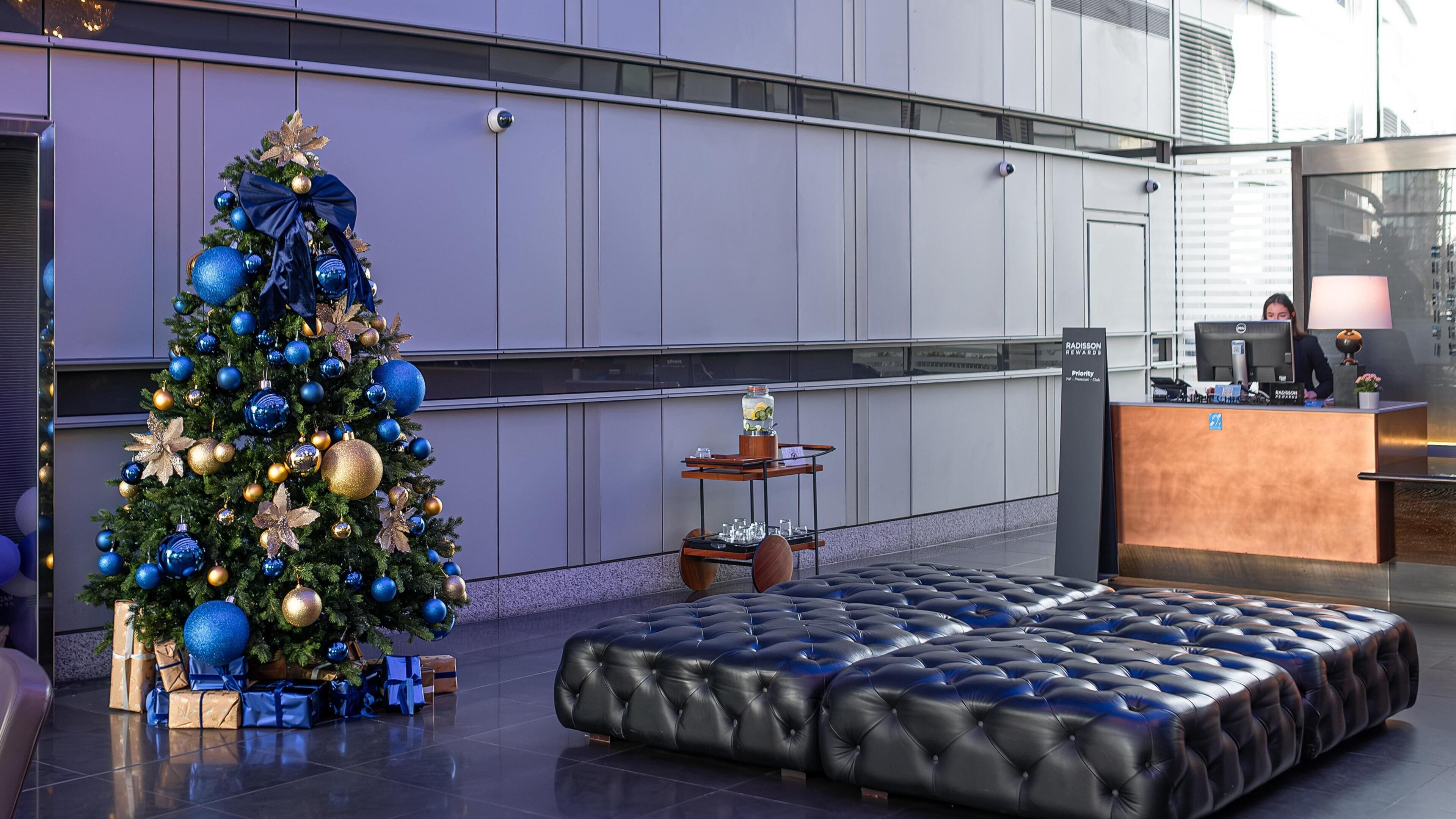 A modern lobby with a Christmas tree, a reception desk, and a leather sofa.