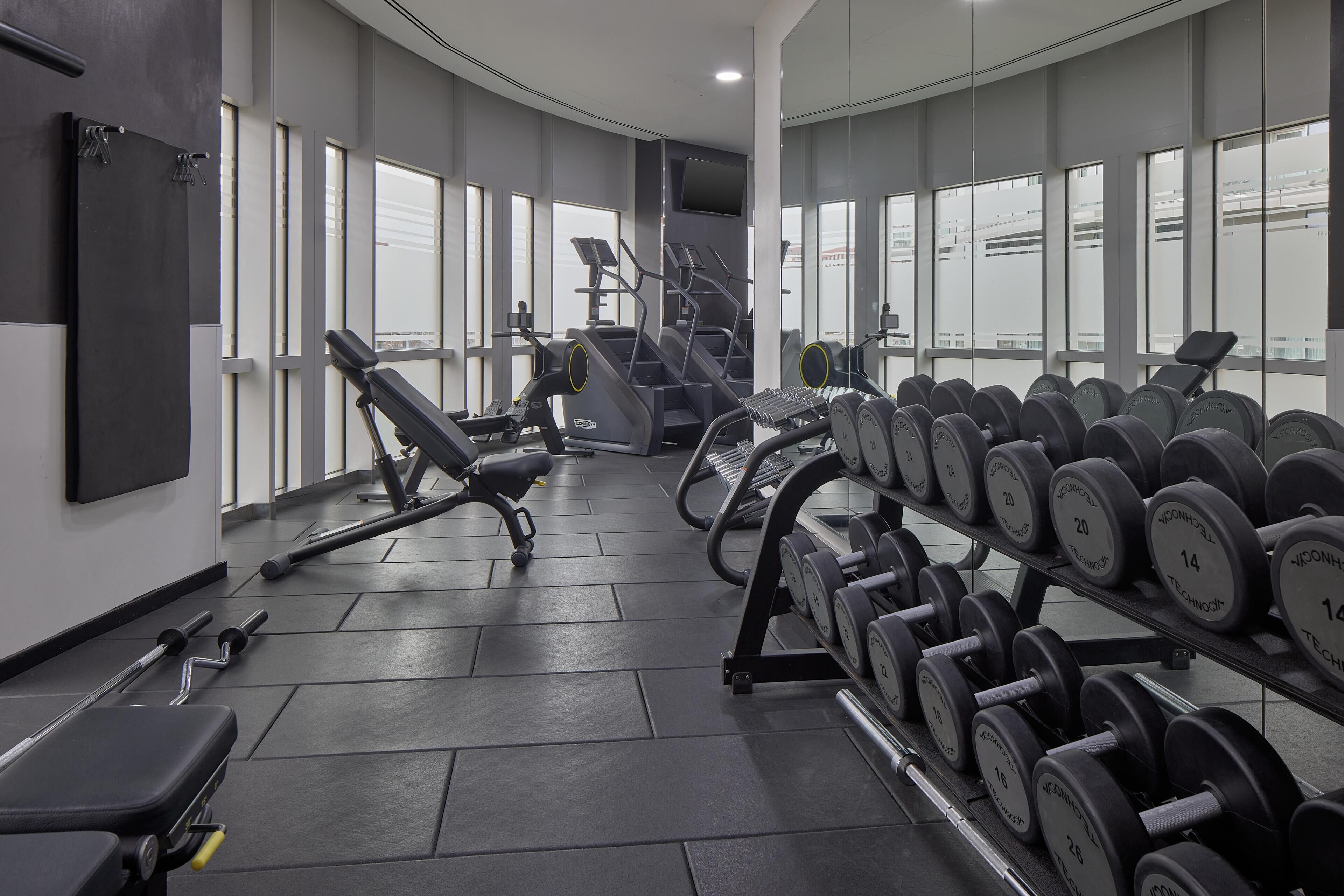 A gym with exercise equipment, including treadmills, dumbbells, and weight benches.