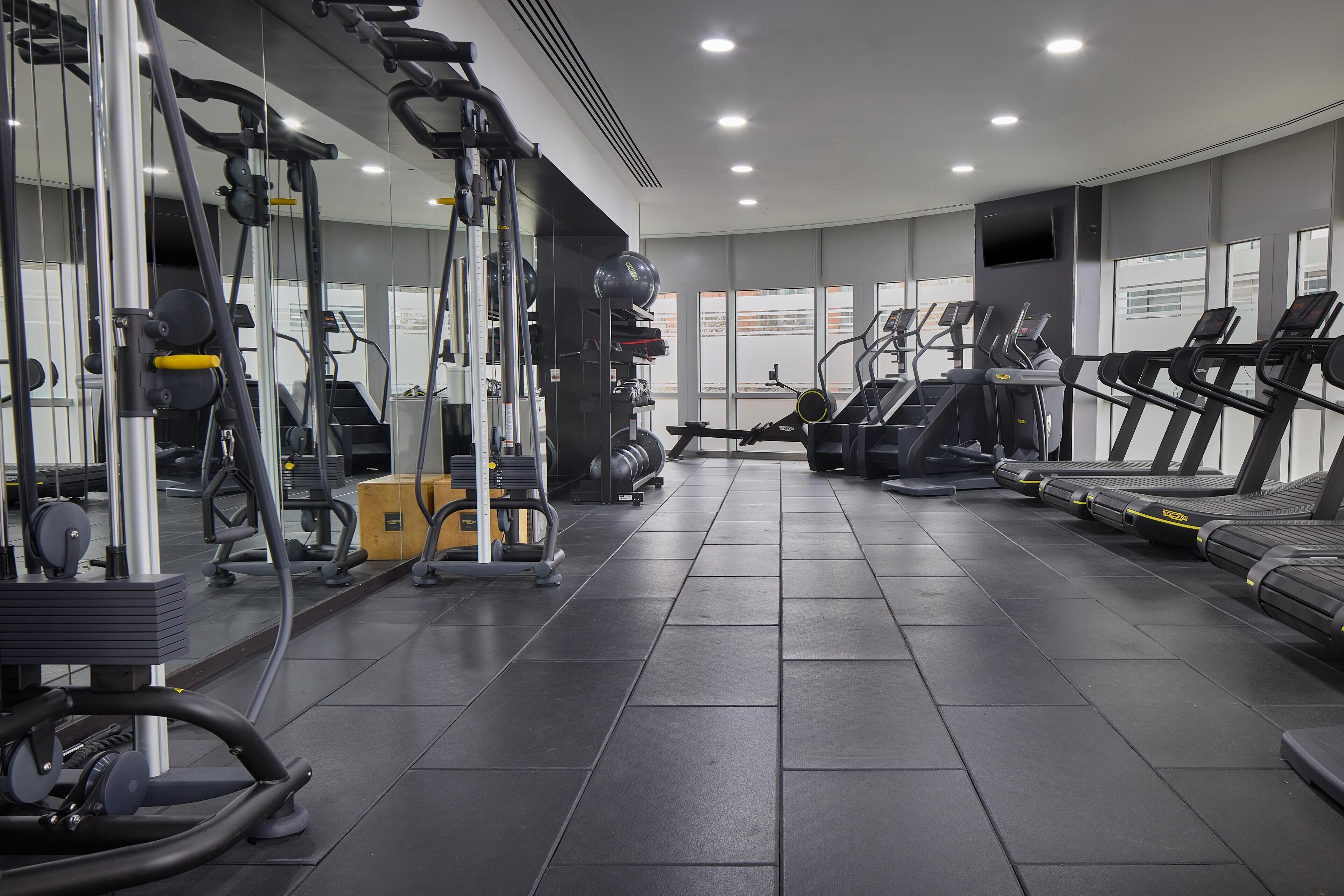 Une salle de sport moderne équipée de divers appareils d’exercice, notamment des tapis de course et des appareils de musculation.