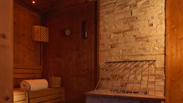 A sauna room with wooden benches, a stone wall, and a tiled floor.