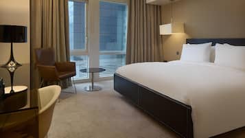 A hotel room with a large bed, a desk, a chair, and a small table.