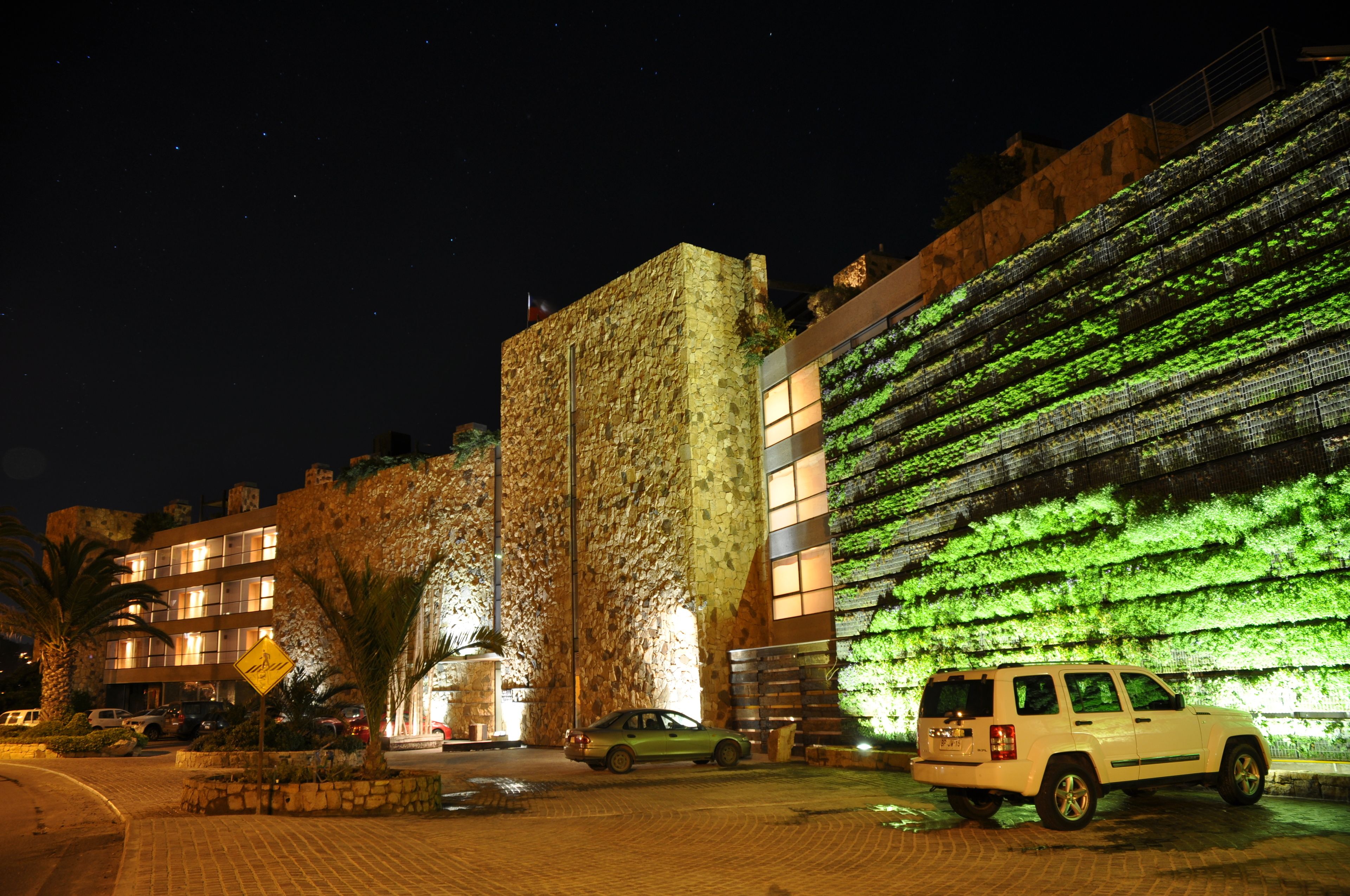Um edifício com fachada de pedra e um jardim vertical verde.