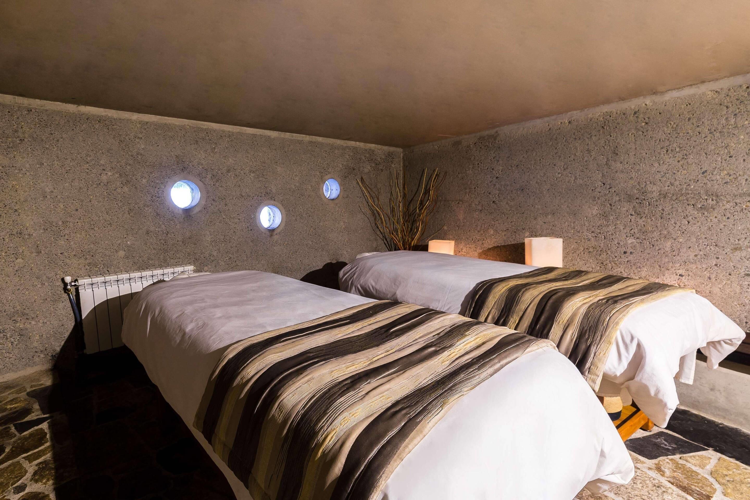 Una habitación con dos camas, suelo de piedra y un radiador.