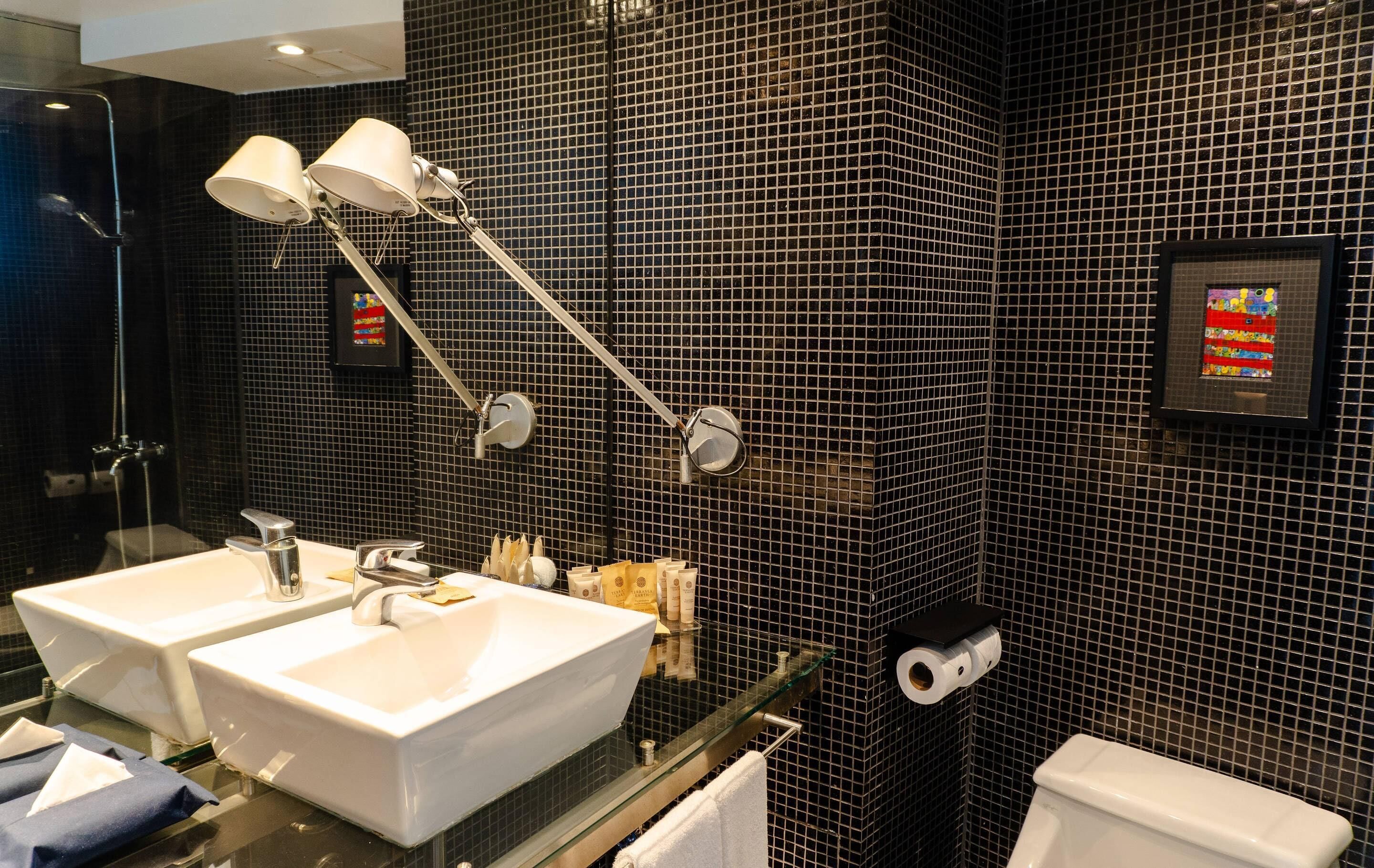 Un baño moderno con dos lavamanos, cabina de ducha de cristal y un inodoro.