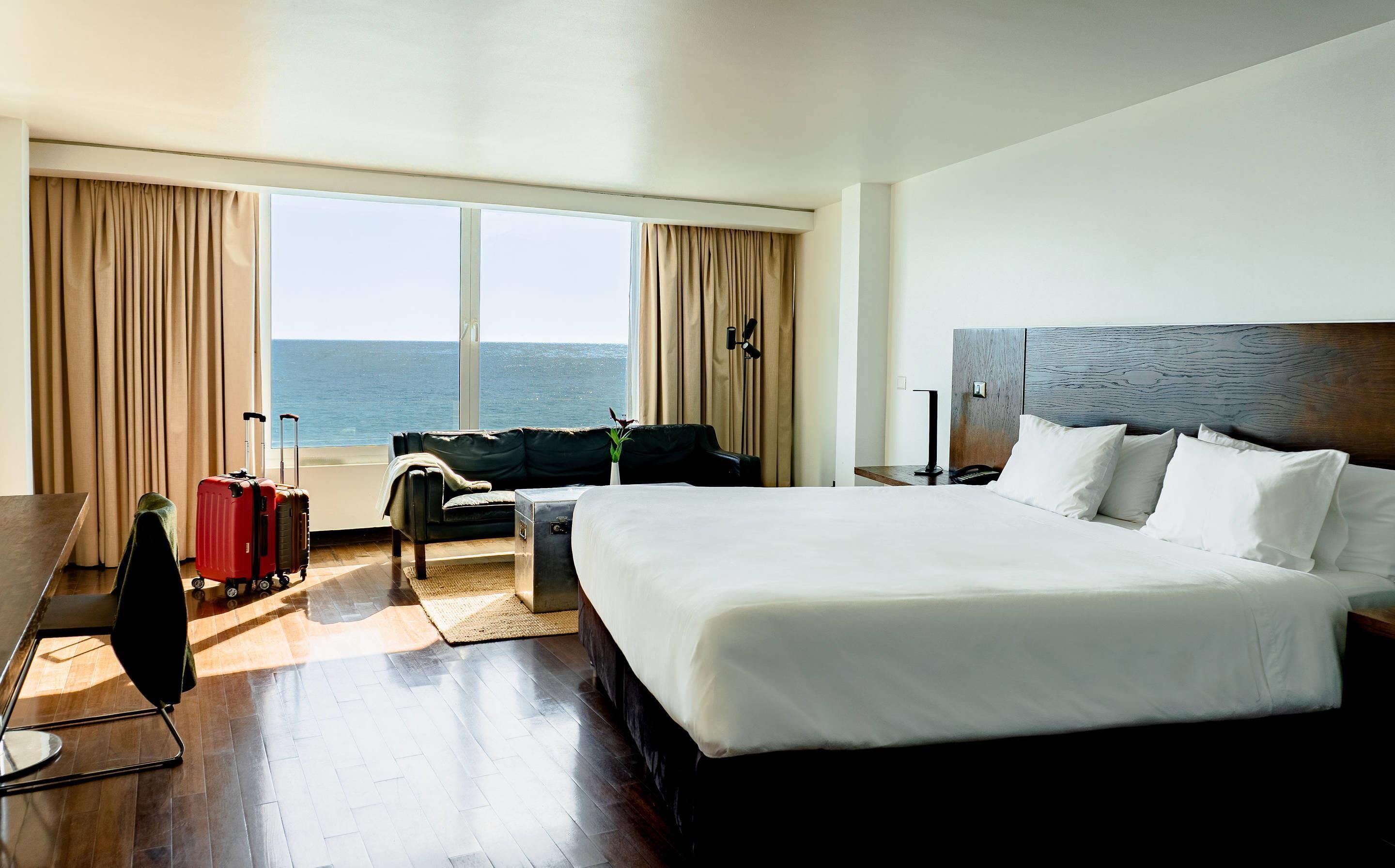 Una camera d'albergo con un letto grande, una scrivania, una sedia, un divano e vista sul mare.