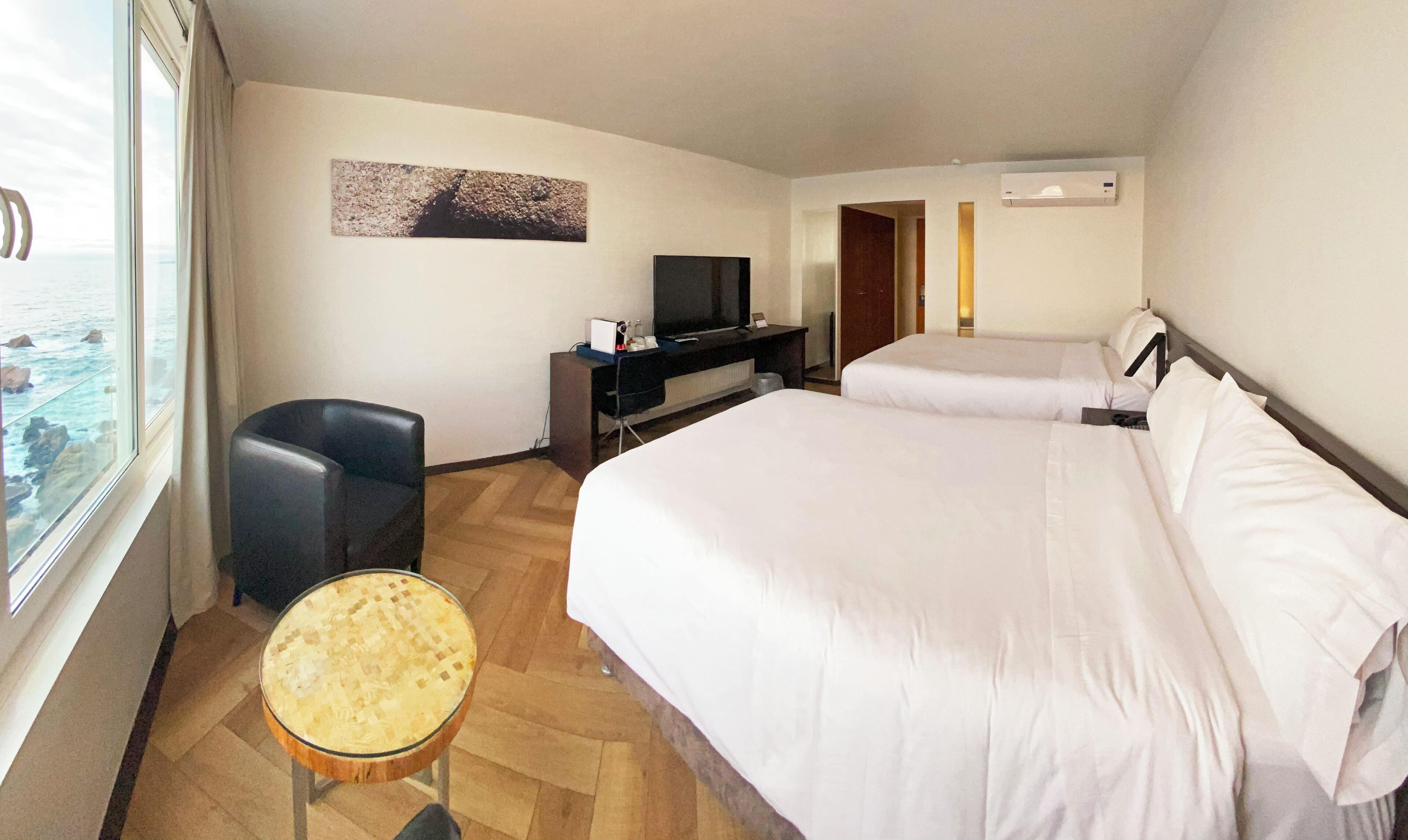 Une chambre d’hôtel avec deux lits, un bureau avec une télévision, une chaise et une petite table.