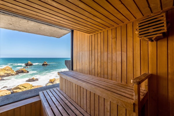 A wooden cabin with a bench and a view of the ocean.
