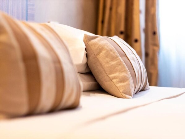 Uma cama com almofadas bege e um edredom branco.