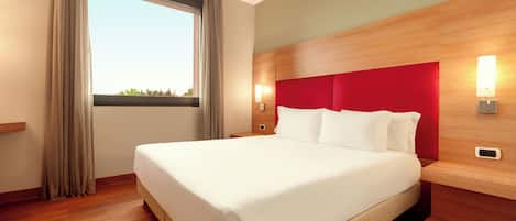 A hotel room with a large bed, wooden headboard, and two bedside lamps.