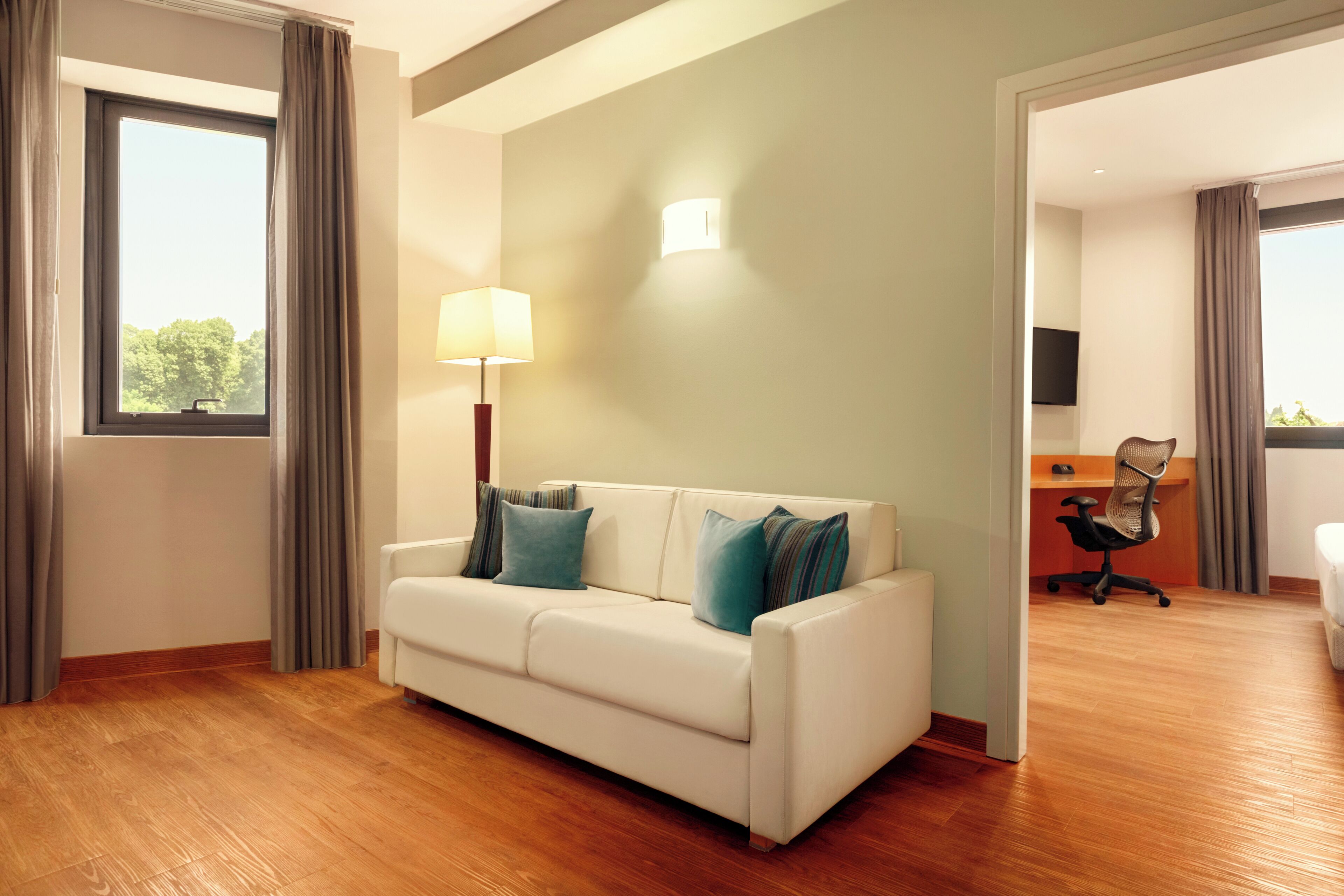 A modern hotel room with a white sofa, a desk, and a chair.