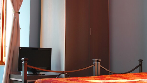 Ein Schlafzimmer mit Bett, Fernseher und Kleiderschrank.