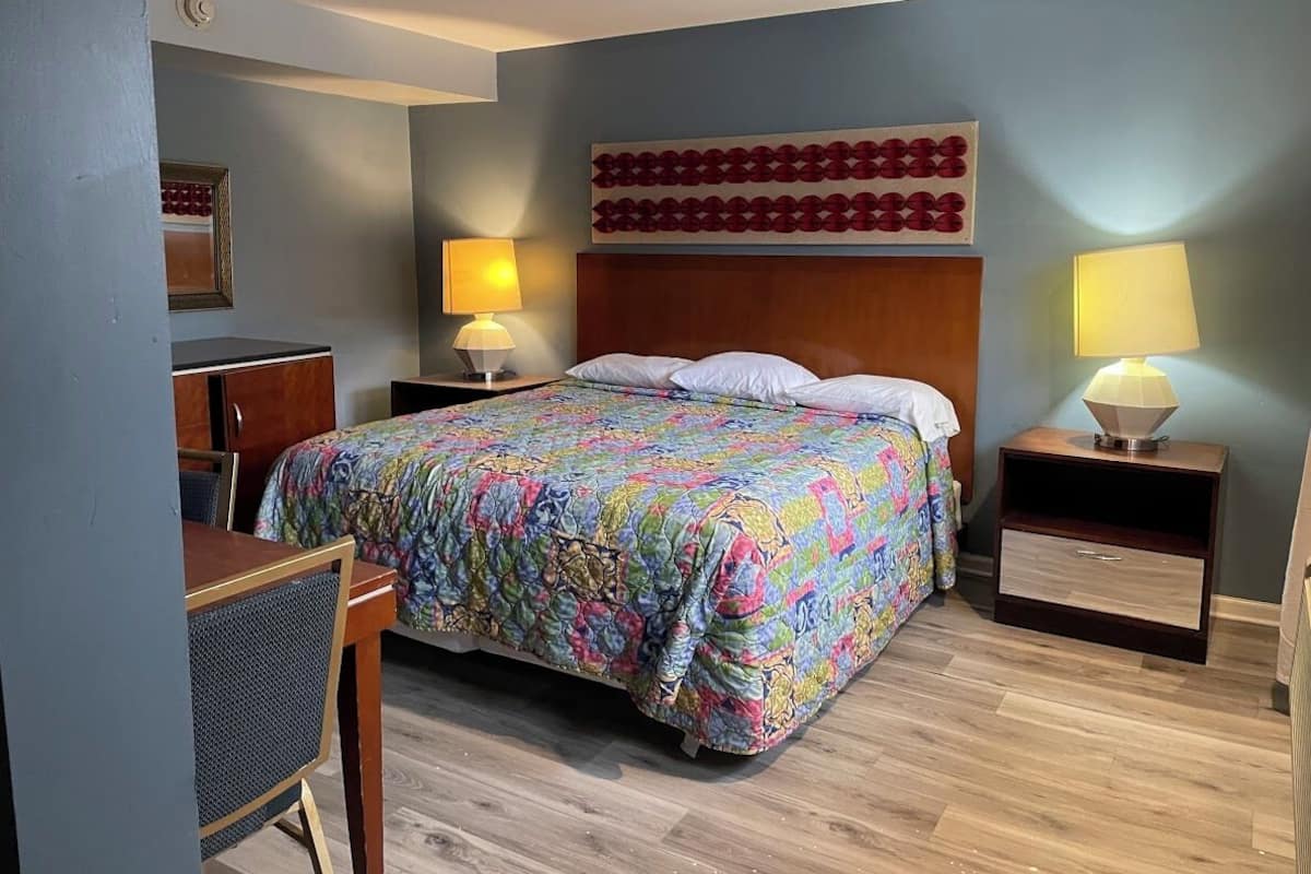 A hotel room with a bed, two bedside tables with lamps, a desk, and a chair.