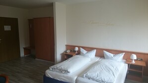 A hotel room with two single beds, wooden headboards, bedside tables with lamps, a wooden wardrobe, and a door. - Landhotel Wasgau (Hauenstein)