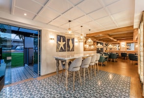 Un área de comedor moderna con un separador de vidrio, una barra y un conjunto de asientos.