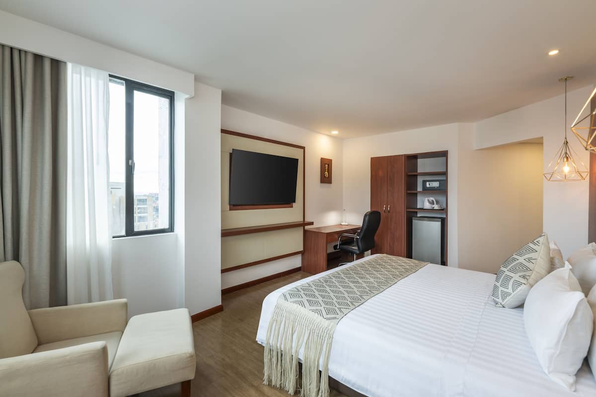 Hotellihuone, jossa on sänky, työpöytä, tuoli, televisio ja vaatekaappi.