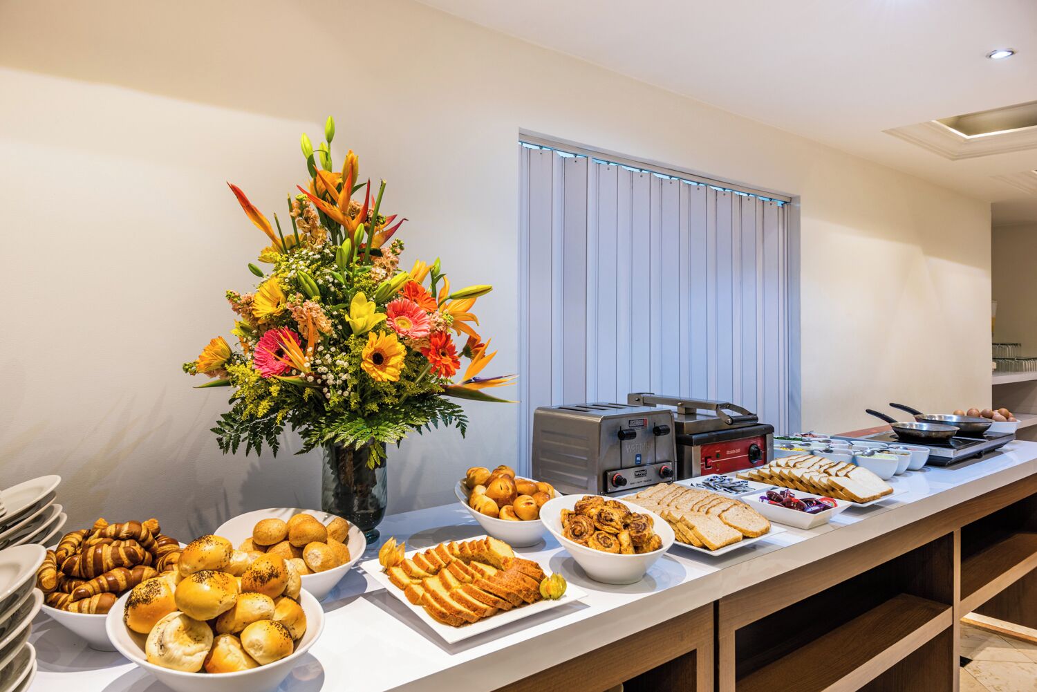 A buffet setup with various food items, a toaster, and a floral centerpiece.