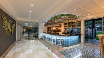 A bar area with a curved counter, bar stools, and a variety of bottles and glasses.