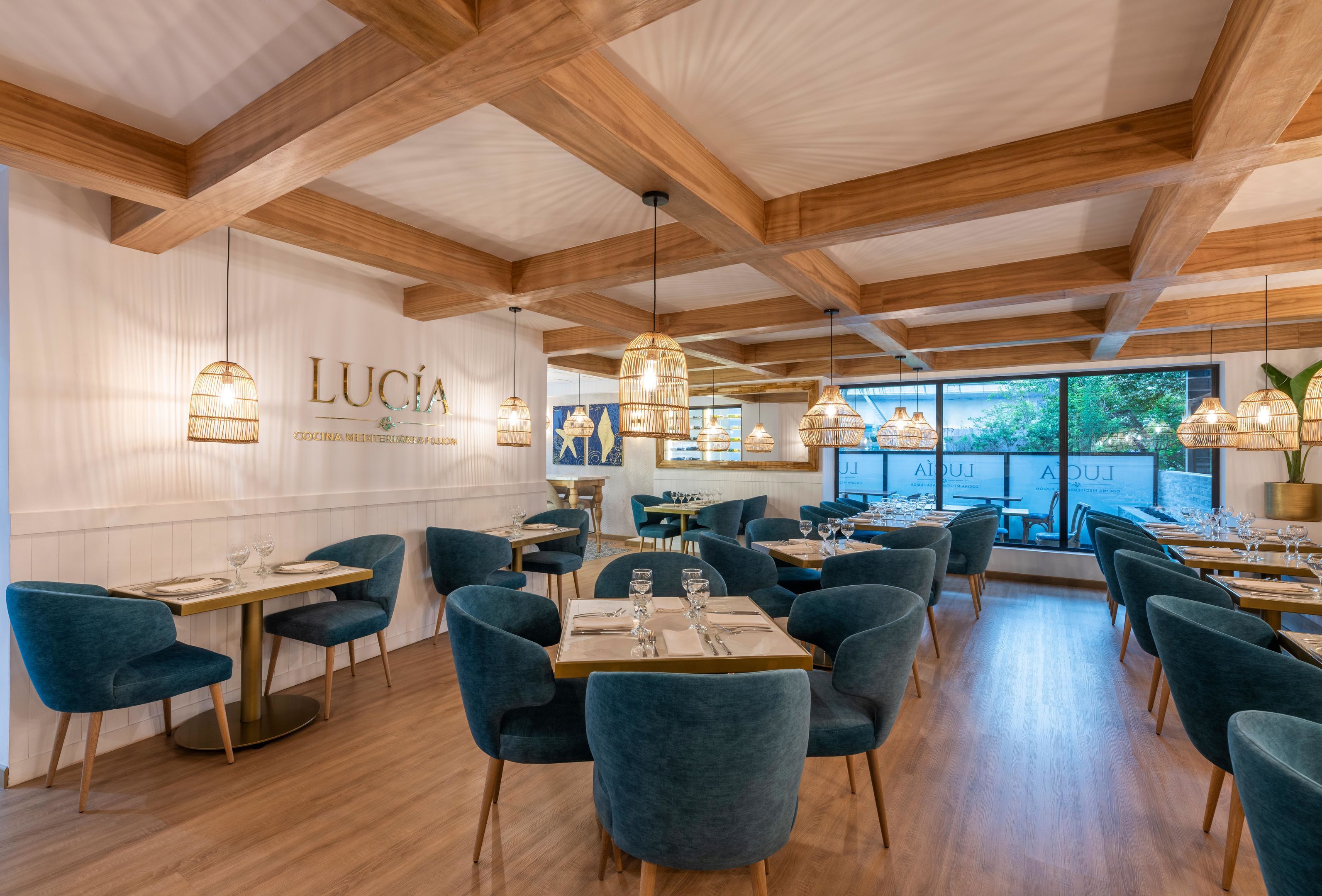 A restaurant interior with wooden beams, blue chairs, and hanging pendant lights.