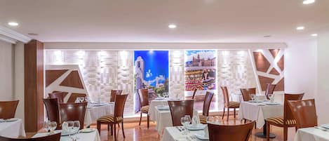 Un restaurante con mesas dispuestas para comer, sillas y un amplio ventanal con vistas.