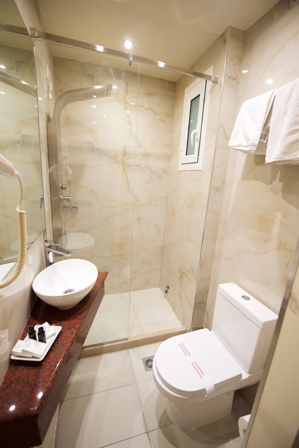 A bathroom with a glass-enclosed shower, a white sink, and a toilet.