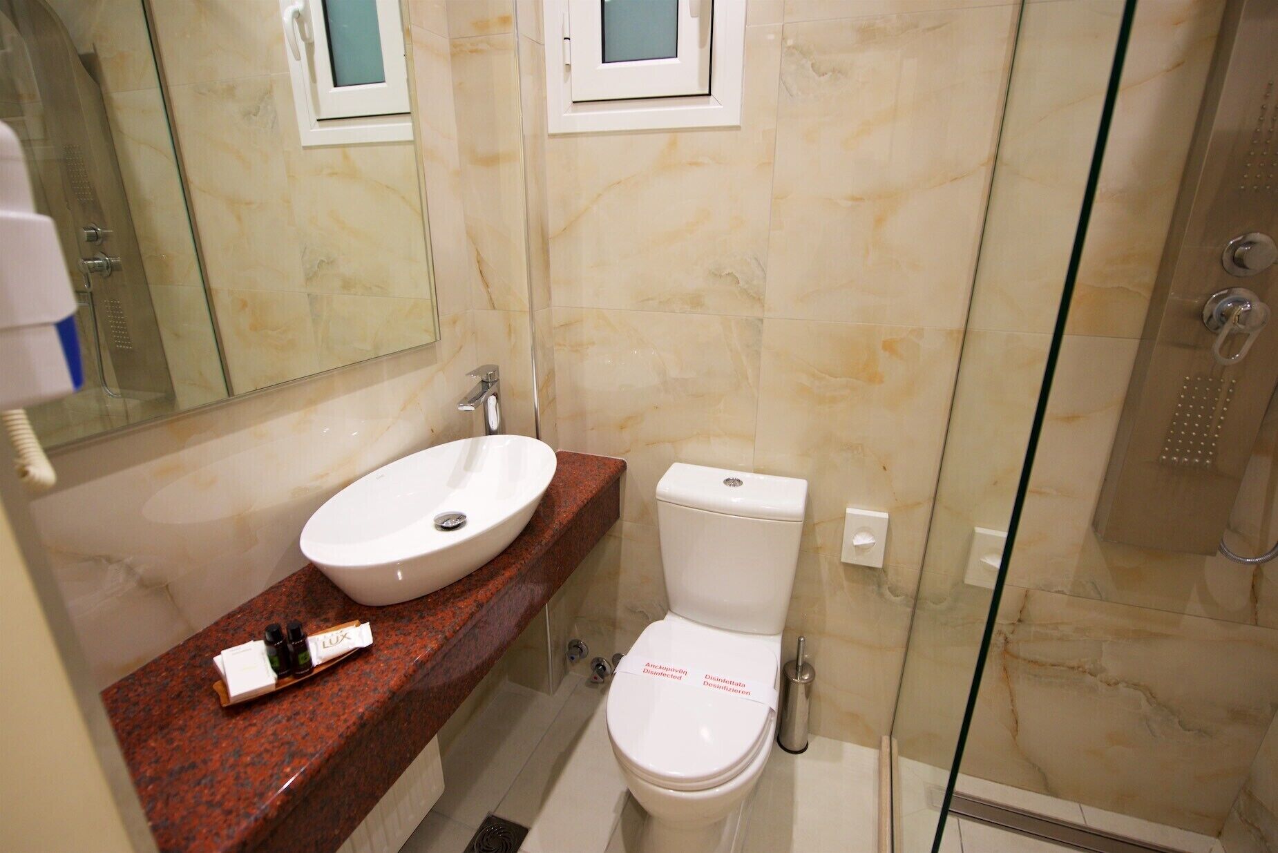 Un baño con lavamanos blanco, inodoro y cabina de ducha con paredes de vidrio.