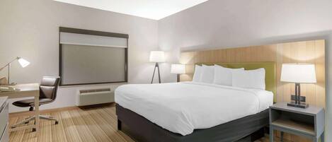 A hotel room with a large bed, bedside tables with lamps, a desk with a chair, and a large window.