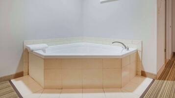 A corner bathroom with a freestanding bathtub, a sink, and a framed picture on the wall.