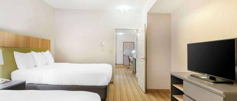 Ein Hotelzimmer mit zwei Betten, einem Fernseher auf einer Kommode und Teppichboden.