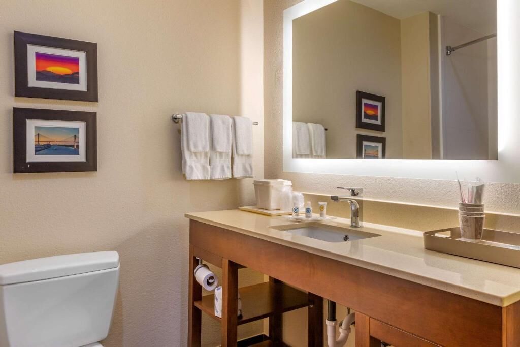 A bathroom with a toilet, a sink with a mirror, and two framed pictures on the wall.