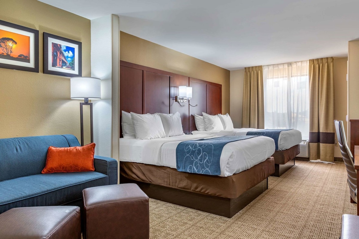 Ein Hotelzimmer mit Bett, einer Couch, einem Schreibtisch und einer Lampe.