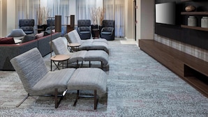 Un salon moderne comprenant un canapé, des fauteuils, une table basse et un téléviseur à écran plat fixé au mur.