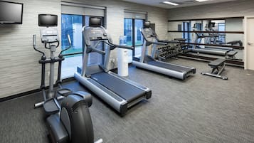 A modern gym with treadmills, elliptical machines, and free weights.