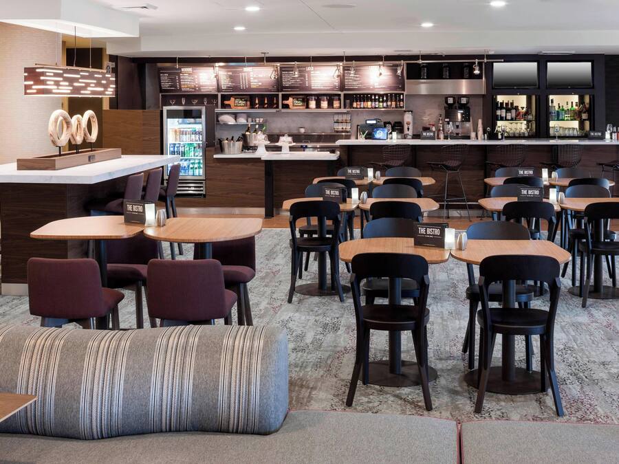 A modern restaurant with a bar area, seating arrangements, and a counter with a menu display.