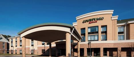 Un hotel Courtyard by Marriott con entrada cubierta y varios pisos.