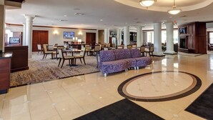 A spacious lobby with a central seating area, a reception desk, and a television screen. - Courtyard by Marriott Hadley Amherst (Hadley)